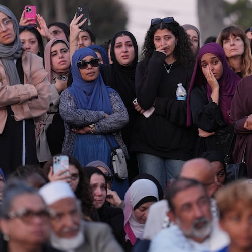 Attendees react as they listen to a speech during a vigil, the day after a shooting, outside of the Islamic Center of San Diego, Tuesday, May 19, 2026, in San Diego. (AP Photo/Jae C. Hong)