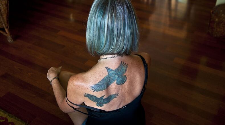 “I’m taking this journey with you,” said Lorri Stonehocker about getting two of her husband’s favorite birds tattooed on her back while posing for a photograph at her home in Spokane Valley on Thursday, Aug. 24, 2017. Her husband passed away in March 2016. She is teaching a first-time class offered through Act 2 on Healthy Grieving. (Kathy Plonka/The Spokesman-Review/TNS)