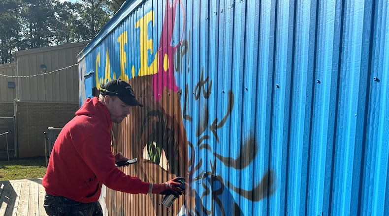 Chastain Clark, an Atlanta based muralist, designed the Dunaire C.A.F.E. Clark  enjoys helping students connect with art in different ways. Students enjoy both participating in the process of mural making and seeing themselves in the finished product, he said. Nedra Rhone/nrhone@ajc.com