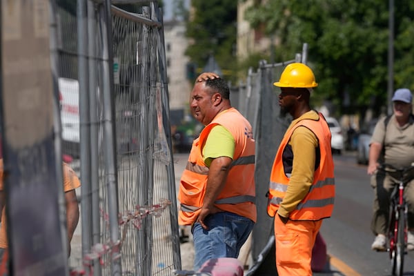 Workers operate under the hot sun at a road construction site, in Milan, Italy, Wednesday, July 2, 2025. (AP Photo/Luca Bruno)