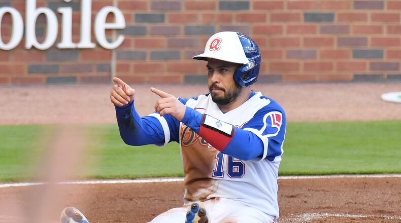 Braves catcher Travis d'Arnaud (16) celebrates after he scored past Philadelphia Phillies catcher J.T. Realmuto (10) on an RBI single by shortstop Dansby Swanson (7) in the first inning Sunday, April 11, 2021, at Truist Park in Atlanta. (Hyosub Shin / Hyosub.Shin@ajc.com)