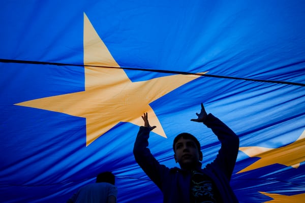 FILE - Children play under an European Union flag during an electoral rally of presidential candidate Nicusor Dan, a week ahead of the second round of the country's presidential election redo in Bucharest, Romania, Sunday, May 11, 2025. (AP Photo/Andreea Alexandru, File)