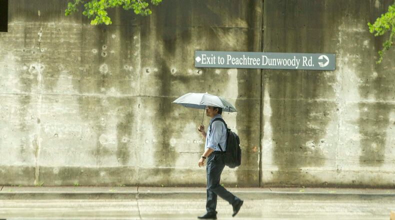 A commuter uses his umbrella to shield himself from an early afternoon shower at the North Springs MARTA transit station in Sandy Springs, Tuesday, May 29, 2018. ALYSSA POINTER/ATLANTA JOURNAL-CONSTITUTION