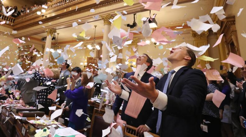 Jared Williams, right, throws a large pile of paper in the air next to his father, state Sen. Michael Williams, R-Cumming, as the Georgia General Assembly’s 2018 session came to a close early Friday. PHOTO / JASON GETZ