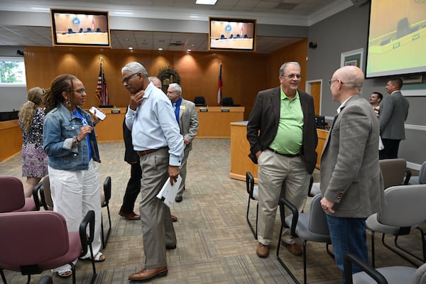 Fayette County Commissioner Charles Rousseau (center left) and Chairman Lee Hearn (center right, in green shirt) speak with attendees at a commission meeting Thursday, Aug. 13, 2026, in Fayetteville. (Hyosub Shin/AJC)