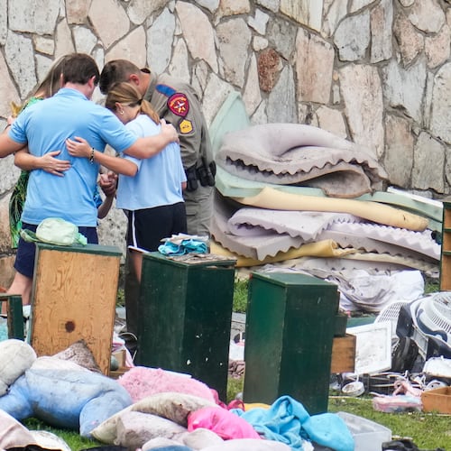 FILE - An officer prays with a family as they pick up items at Camp Mystic in Hunt, Texas, July 9, 2025. (AP Photo/Ashley Landis, File)
