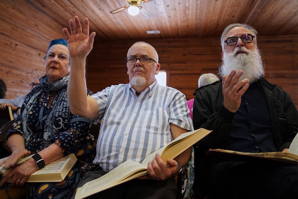 From left, Lisa Bennett, Wade Kotter, and David Stead, Bennett's husband, sing in the alto section during a Sacred Harp singing event at Holly Springs Primitive Baptist Church in Bremen, Ga., on Saturday, March 22, 2025. (AP Photo/Jessie Wardarski)