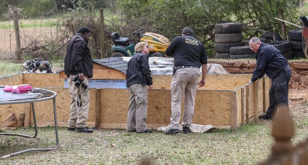 Clayton County police investigate the doghouse area where the children were found. JOHN SPINK / JSPINK@AJC.COM