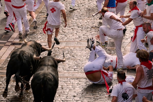 Revelers run with bulls from Fuente Ymbro ranch during the first day of the running of the bulls at the San Fermín fiestas in Pamplona, Spain, Monday, July 7, 2025. (AP Photo/Miguel Oses)