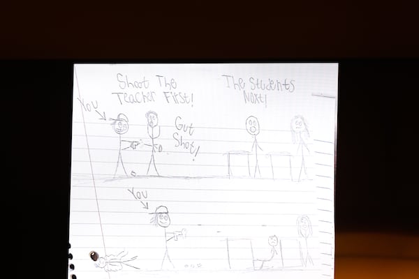 A screen displays the words “Shoot the teacher first” and other phrases from the notebook of the Apalachee High School shooter at his plea hearing at Barrow County Superior Court in Winder on July 24, 2026. (Arvin Temkar/AJC)