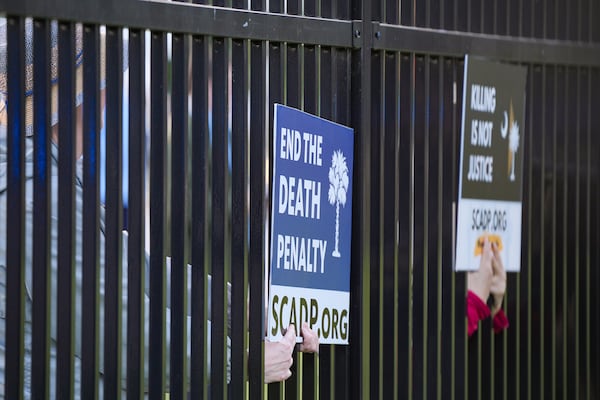 Protestors put their signs inside the Department of Corrections fence prior to the scheduled execution of South Carolina inmate Mikal Mahdi in Columbia, S.C., Friday, April 11, 2025. (AP Photo/David Yeazell)