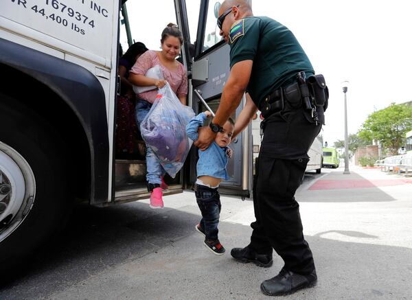A transport officer, right, helps immigrants Dilma Araceley Riveria Hernandez, and her son, Anderson Alvarado, 2, get off the bus after they were processed and released by U.S. Customs and Border Protection, Sunday, June 24, 2018, in McAllen, Texas. (AP Photo/David J. Phillip)