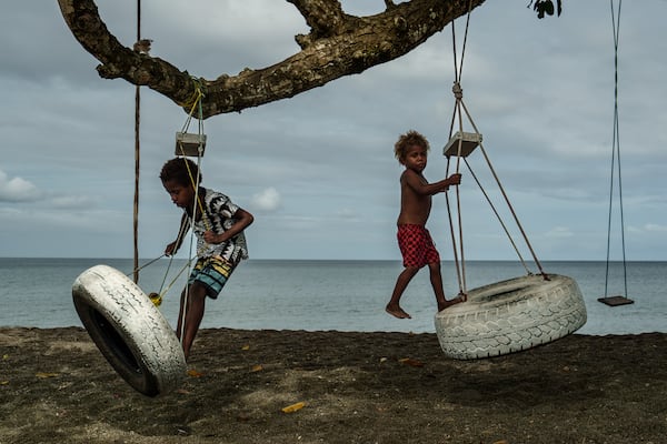 Children play on an uprooted tree along a beach in Mele, Vanuatu that was once lined with vegetation, now largely lost to storms, erosion and other environmental pressures on Saturday, July 19, 2025. (AP Photo/Annika Hammerschlag)