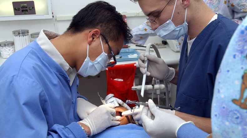 Dr. Thein “Tim” Pham, left, a co-founder of Kool Smiles, is seen working on a filling of a 5-year-old girl in 2002. The company will payout $24 million after a court settlement.