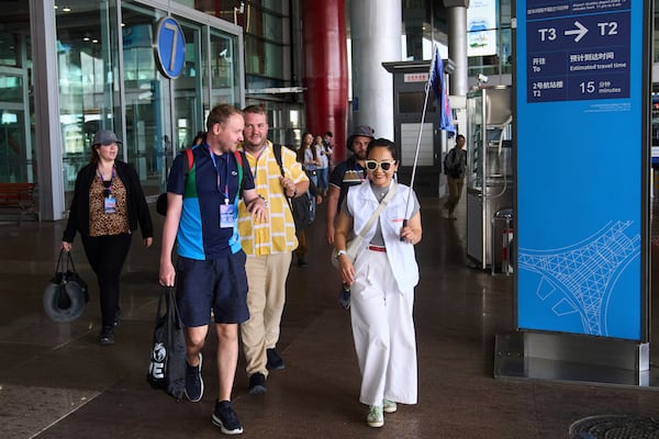 A tour guide leads tourists to the shutter bus to take a half-day tour to the tourism destination which offered by a travel agency Trip.com Group, at the Beijing Capital International Airport, in Beijing on June 15, 2025. (AP Photo/Andy Wong)