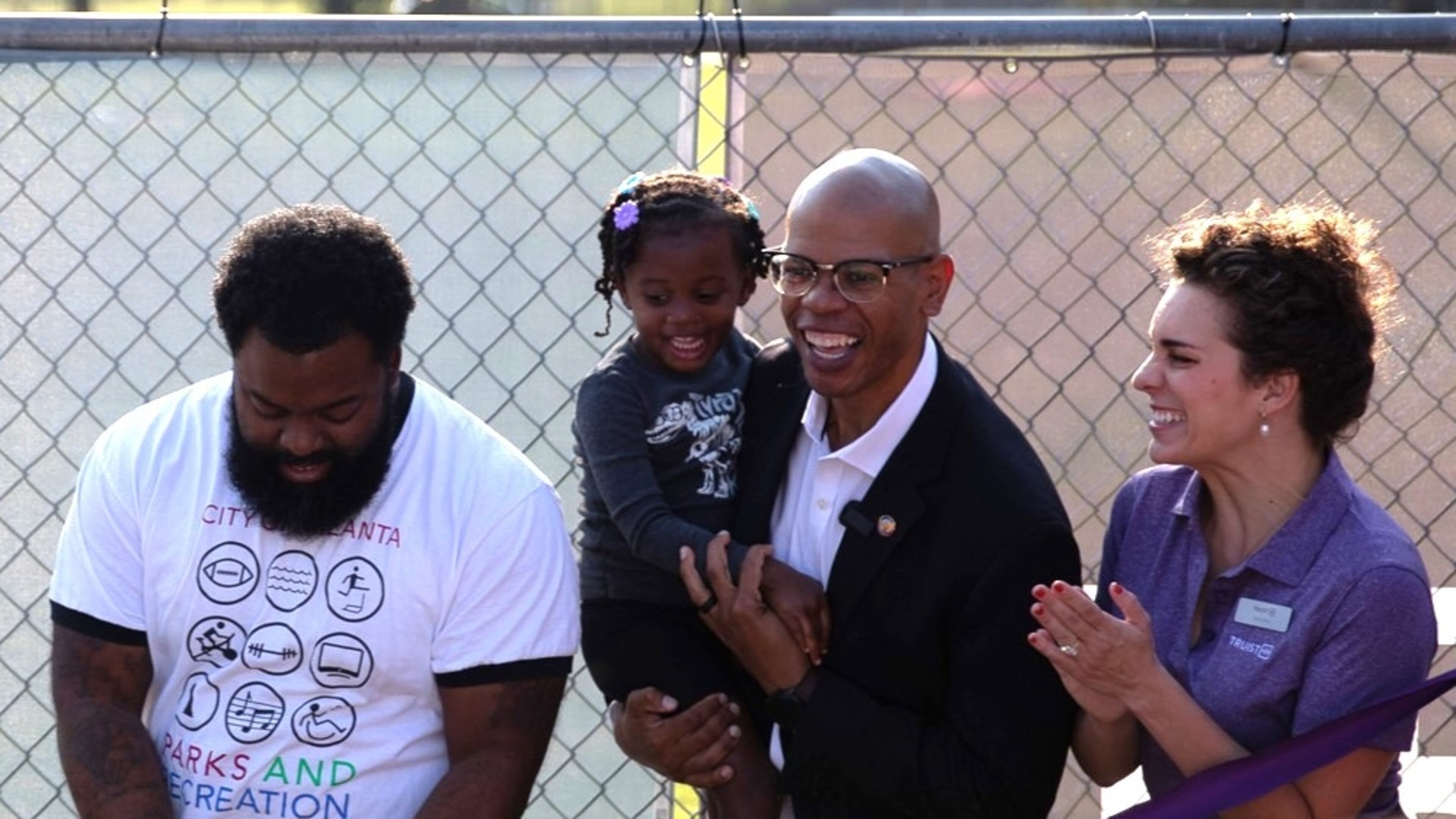 Council member Jason Dozier and his daughter Rayna (center) celebrate upgrades made to Rosa L. Burney Park in Mechanicsville. He and his daughter were hit by a car while biking. (Riley Bunch/AJC)