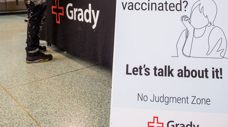 In this file photo, Grady Hospital staffs a vaccine question desk in the main lobby of the hospital. Minnette Hardeman, left, who isn’t vaccinated talks with Emory professor Dr. Kimberly Manning, seated, who is available in the 'no judgement zone' for anyone with concerns or questions still looking for information on the vaccines. (Jenni Girtman for The Atlanta Journal-Constitution)