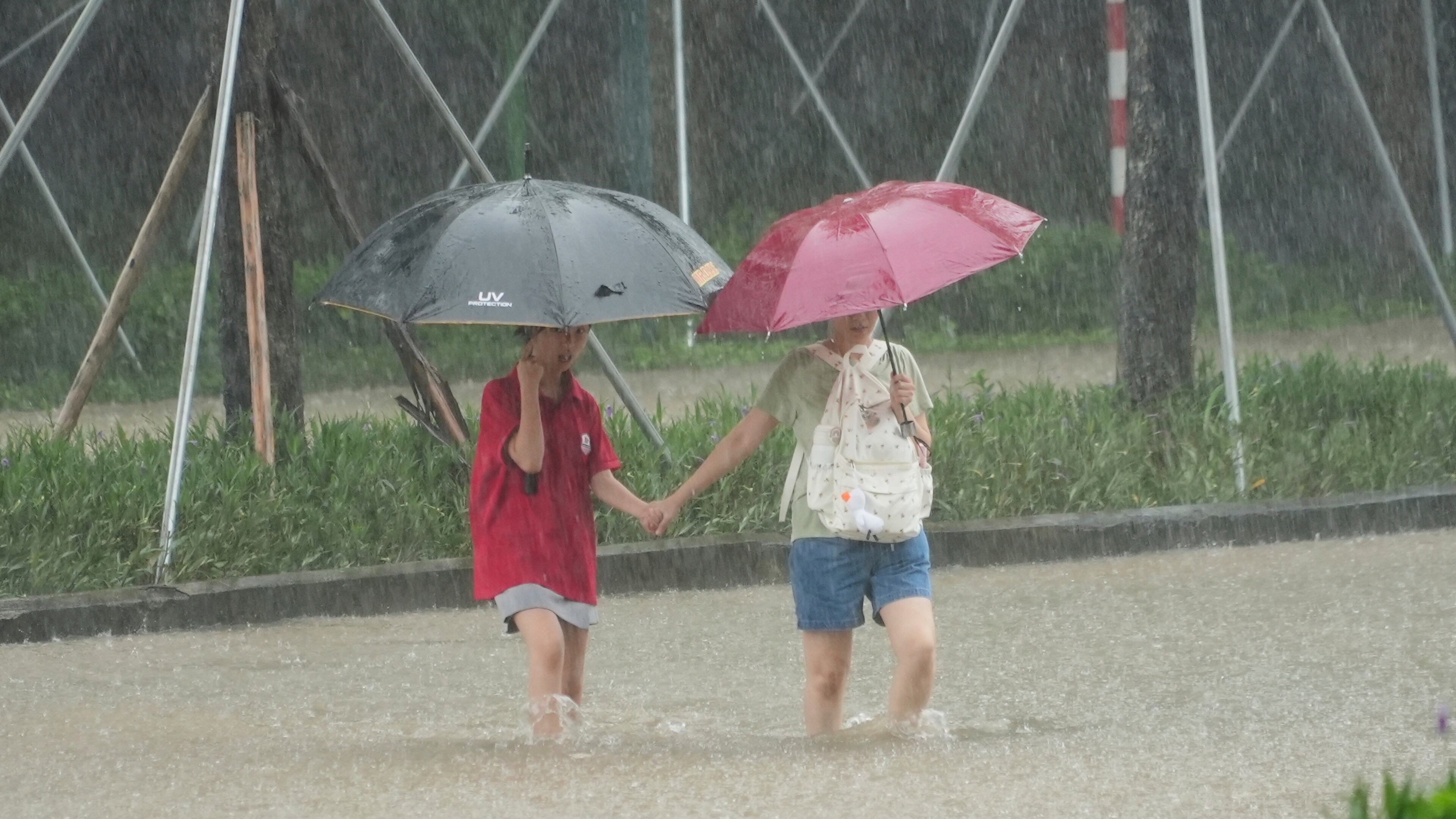 People cross a flooded street in the rain caused by Typhoon Kajiki in Hanoi, Vietnam, Tuesday, Aug. 26, 2025. (AP Photo/Hau Dinh)