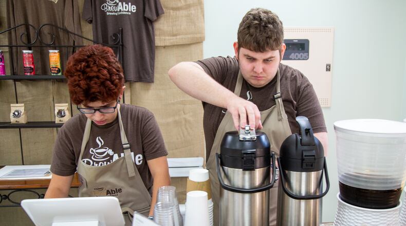 Meggy Kay (left) & Griffin Rudd work at the BrewAble Cafe inside the Alpharetta Community Center in Alpharetta. The coffee shop was set up by the city of Alpharetta and community volunteers to solve community issues of un- and under-employment and isolation for people with intellectual and developmental disabilities. (Photo by Phil Skinner)