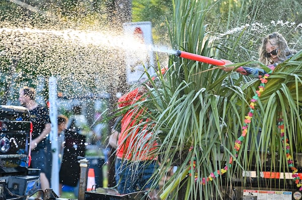 A parade participant shoots a water gun from behind the cover of palm fronds during Friday's Tybee Beach Bum Parade. (Sarah Peacock for the AJC)
