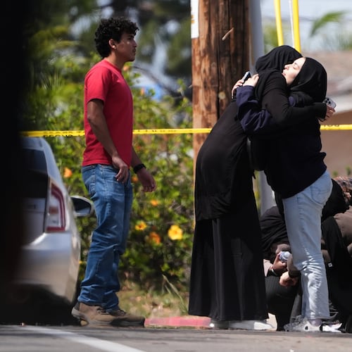 FILE - People embrace near the scene of a shooting outside the Islamic Center in San Diego, May 18, 2026, (AP Photo/Gregory Bull, File)