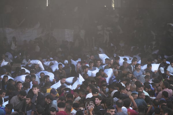 Palestinians carry bags of flour after storming a U.N. World Food Program warehouse in Zawaida, Central Gaza Strip, on Wednesday, May 28, 2025. (AP Photo/Abdel Kareem Hana)