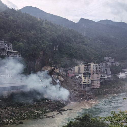 In this photo taken and provided by Mimosa shows smoke rise as resident buildings toppled by rocks and muds following a landslide in Pengshui County in southwestern China's Chongqing on Friday, July 17, 2026. (Mimama via AP)