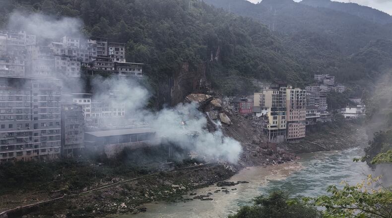 In this photo taken and provided by Mimosa shows smoke rise as resident buildings toppled by rocks and muds following a landslide in Pengshui County in southwestern China's Chongqing on Friday, July 17, 2026. (Mimama via AP)