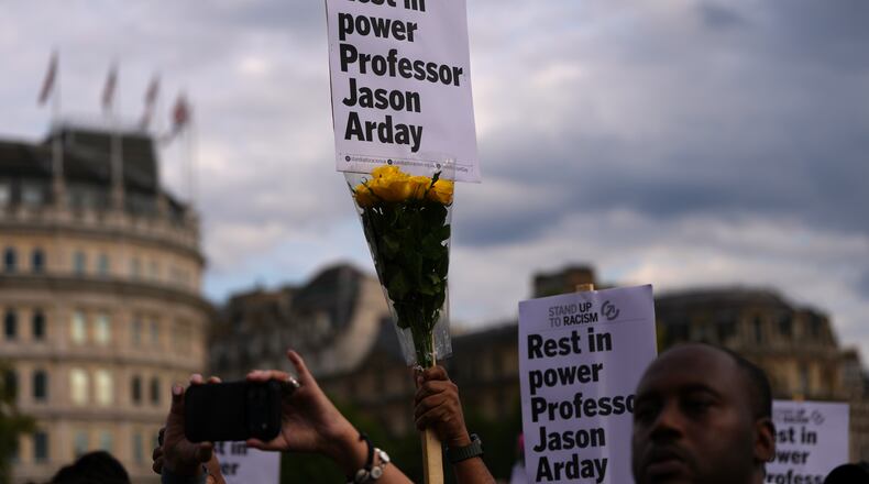 FILE - People attending a vigil held by Stand Up to Racism, in memory of late University of Cambridge professor Jason Arday, hold up signs at Trafalgar Square in London, on Aug. 17, 2026. (AP Photo/Kirsty Wigglesworth, File)