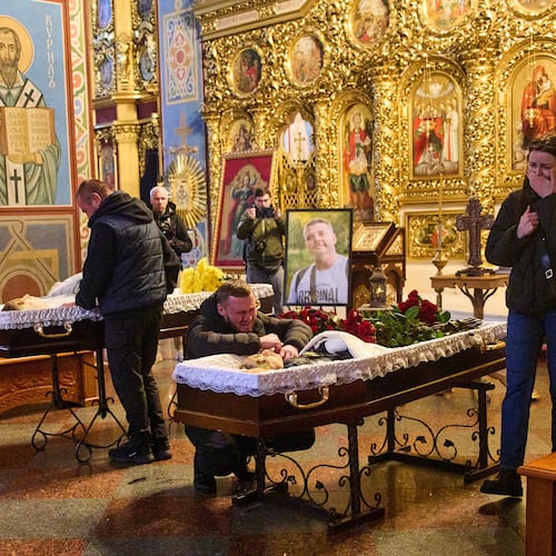 Relatives, colleagues and friends of two Ukrainian 43-year-old journalists Olena Hubanova, who worked under the pseudonym Alyona Gramova, and cameraman Yevhen Karmazin, who were killed on Thursday, Oct. 23, when a Russian Lancet drone hit their vehicle in Ukraine's Kramatorsk around 20 kilometres from the front line, mourn over their coffins during a funeral service at St. Michael Monastery in Kyiv, Ukraine, Monday, Oct. 27, 2025. (AP Photo/Efrem Lukatsky)