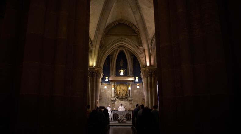 A priest celebrates Mass in the crypt of Antoni Gaudí beneath the Sagrada Familia while crowds of visitors fill the basilica above in Barcelona, Spain, May 15, 2026. (AP Photo/Emilio Morenatti)