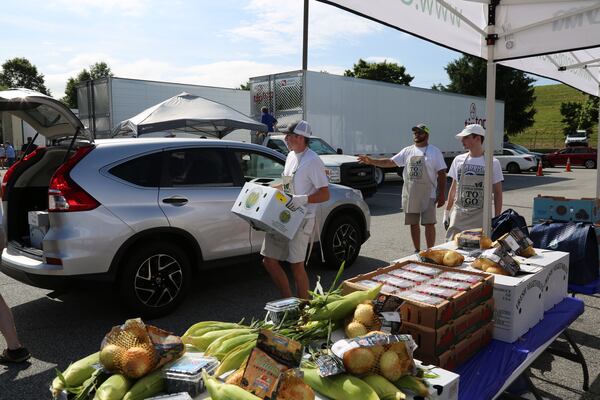 Staff and volunteers coordinated by JRM Management, a local event company, work to load the trunk of a car with fresh Georgia-grown produce during the May Georgia Grown market in Cobb County. The state Department of Agriculture and other agencies set up the box sales to help Georgia vegetable farmers, who were facing lost sales from shut-downs caused by the spread of COVID-19 in the spring of 2020.
