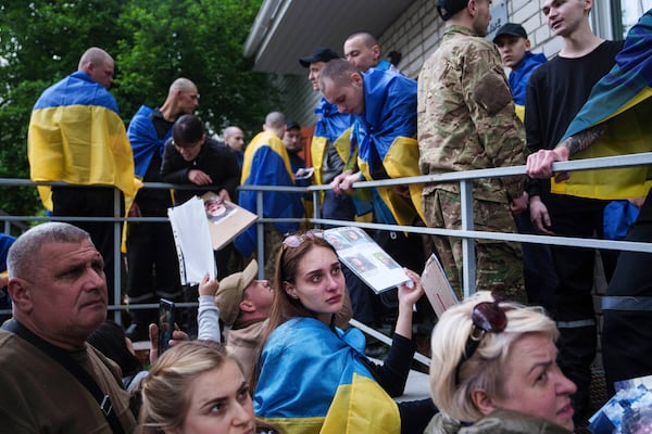 FILE - Relatives of missing and imprisoned Ukrainian soldiers show photographs to servicemen returning from captivity in a POW exchange in Ukraine, Tuesday, May 6, 2025. (AP Photo/Evgeniy Maloletka, File)