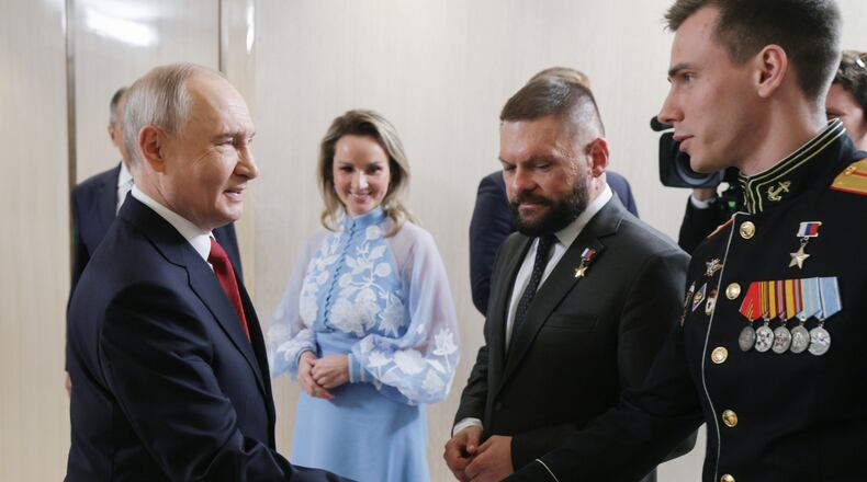 FILE - Russian President Vladimir Putin, left, greets Vladislav Golovin, right, during a meeting with the leaders of the United Russia political party as Presidential Commissioner for Children's Rights Maria Lvova-Belova, center, and military correspondent Yevgeny Poddubny, second right, in Moscow on Saturday, Sept. 5, 2026. (Gavriil Grigorov/Sputnik, Kremlin Pool Photo via AP, File)