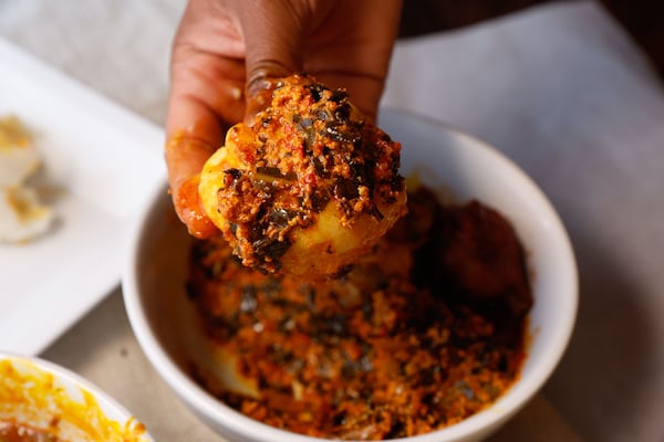 Fufu dipped into egusi at Le Nouveau Maquis creates a warm and filling bite. (Natrice Miller/AJC)