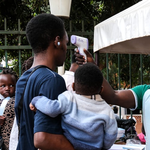 A health official uses a thermometer to screen people in front of Kibuli Muslim Hospital in Kampala, Uganda, Saturday, May 16, 2026. (AP Photo/ Hajarah Nalwadda)