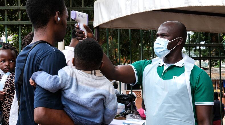 A health official uses a thermometer to screen people in front of Kibuli Muslim Hospital in Kampala, Uganda, Saturday, May 16, 2026. (AP Photo/ Hajarah Nalwadda)