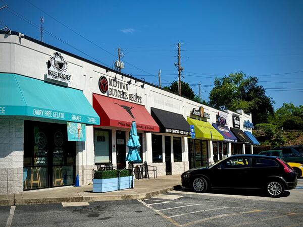 A shopping center with colorful sunshades and cars in the parking lot.
