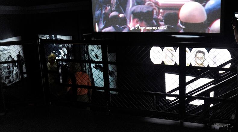 From a church pew bench, visitors can view a video showing the plane bearing the coffin of Martin Luther King, Jr., at an exhibit in the National Center for Civil and Human Rights Tuesday, June 10, 2014, in Atlanta. The main exhibits include: the King papers on the first floor, the second floor main entrance, open space and mural, the lunch counter, interactive TV displays, Freedom Rider Bus, and stained glass portraits of four girls killed during violence in Alabama, while the third floor showcases the global human rights footprint with intimate cone-shaped movie theaters and a villains and champions exhibit. David Tulis / AJC Special