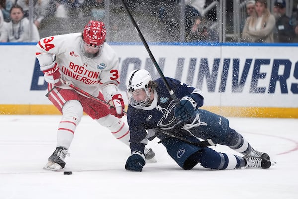 Penn State's Casey Aman, right, falls after colliding with Boston University's Cole Eiserman (34) during the third period in a semifinal game in the NCAA Frozen Four men's college hockey tournament, Thursday, April 10, 2025, in St. Louis (AP Photo/Jeff Roberson)