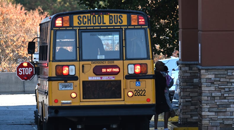 A Gwinnett County school bus drops off a young child at the entry of an extended-stay hotel in Duluth on Tuesday, Nov. 7, 2023. It was one of at least 10 school buses that stopped there that afternoon. Student homelessness is rising. Under federal law, students who live in extended-stay hotels are considered to be homeless, and school districts must transport them to the school they attended before becoming homeless, or to the school they chose after. That means multiple buses from many schools visiting each such hotel. (Hyosub Shin / Hyosub.Shin@ajc.com)