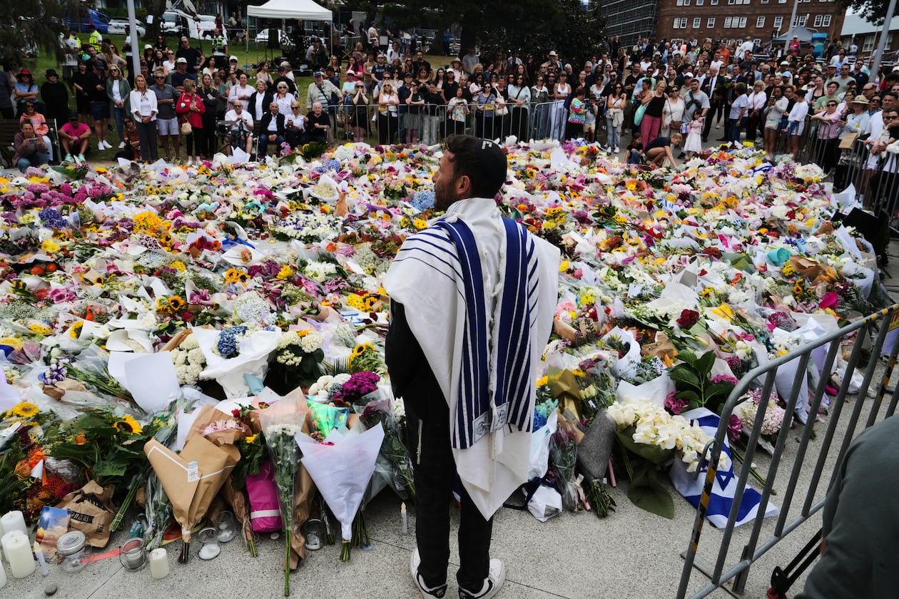 Rabbi Yossi Friedman speaks to people gathering at a flower memorial by the Bondi Pavilion at Bondi Beach on Tuesday, Dec. 16, 2025, following Sunday's shooting in Sydney, Australia. (AP Photo/Mark Baker)