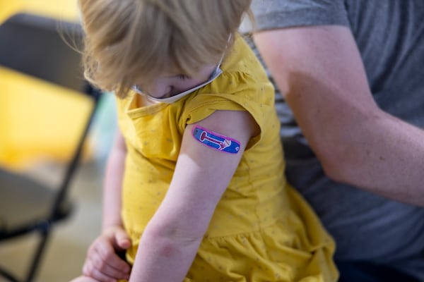 A child looks at a blue Band-Aid after receiving a vaccine. (Jenn Ackerman/The New York Times)