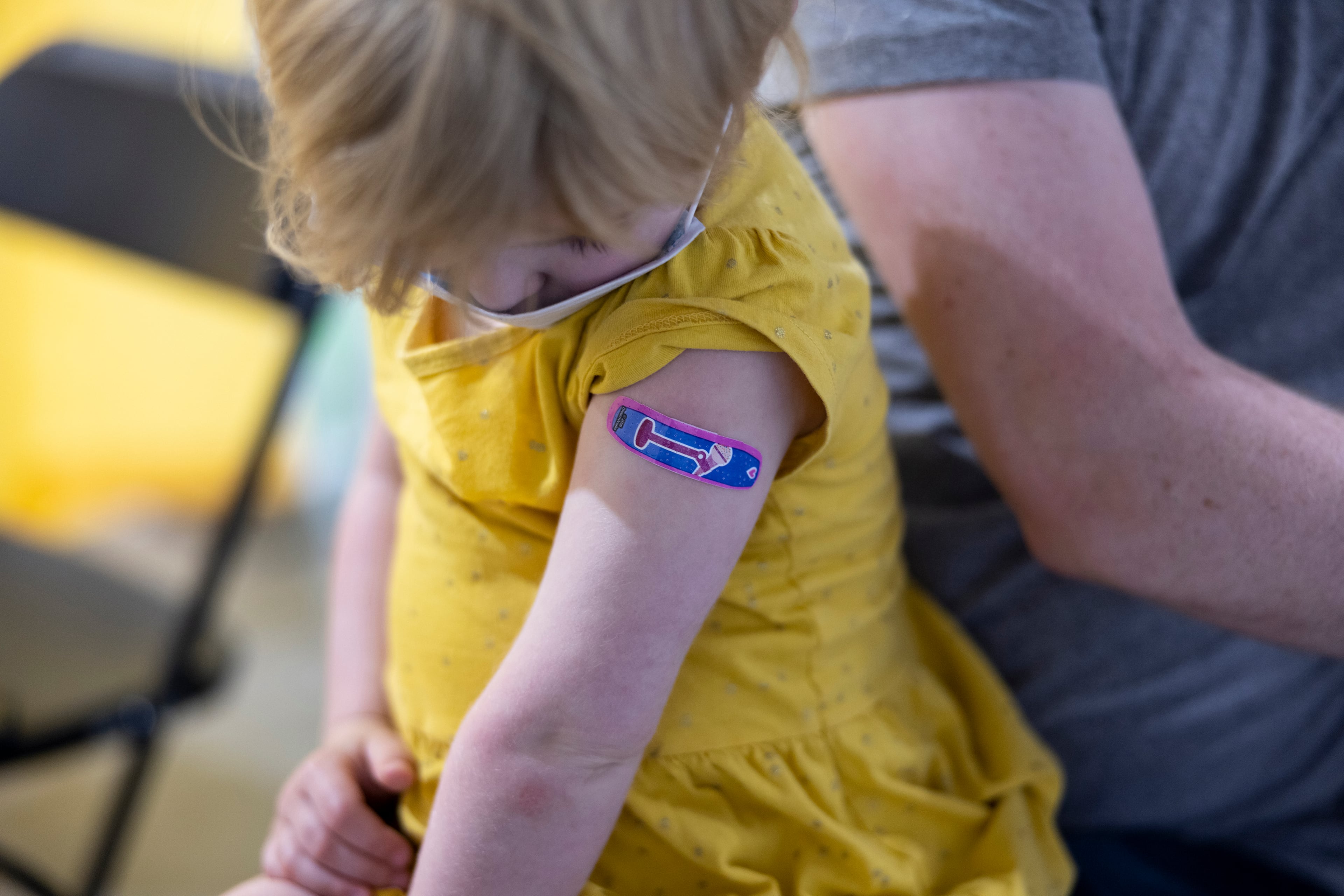 A child looks at a blue Band-Aid after receiving a vaccine. (Jenn Ackerman/The New York Times)