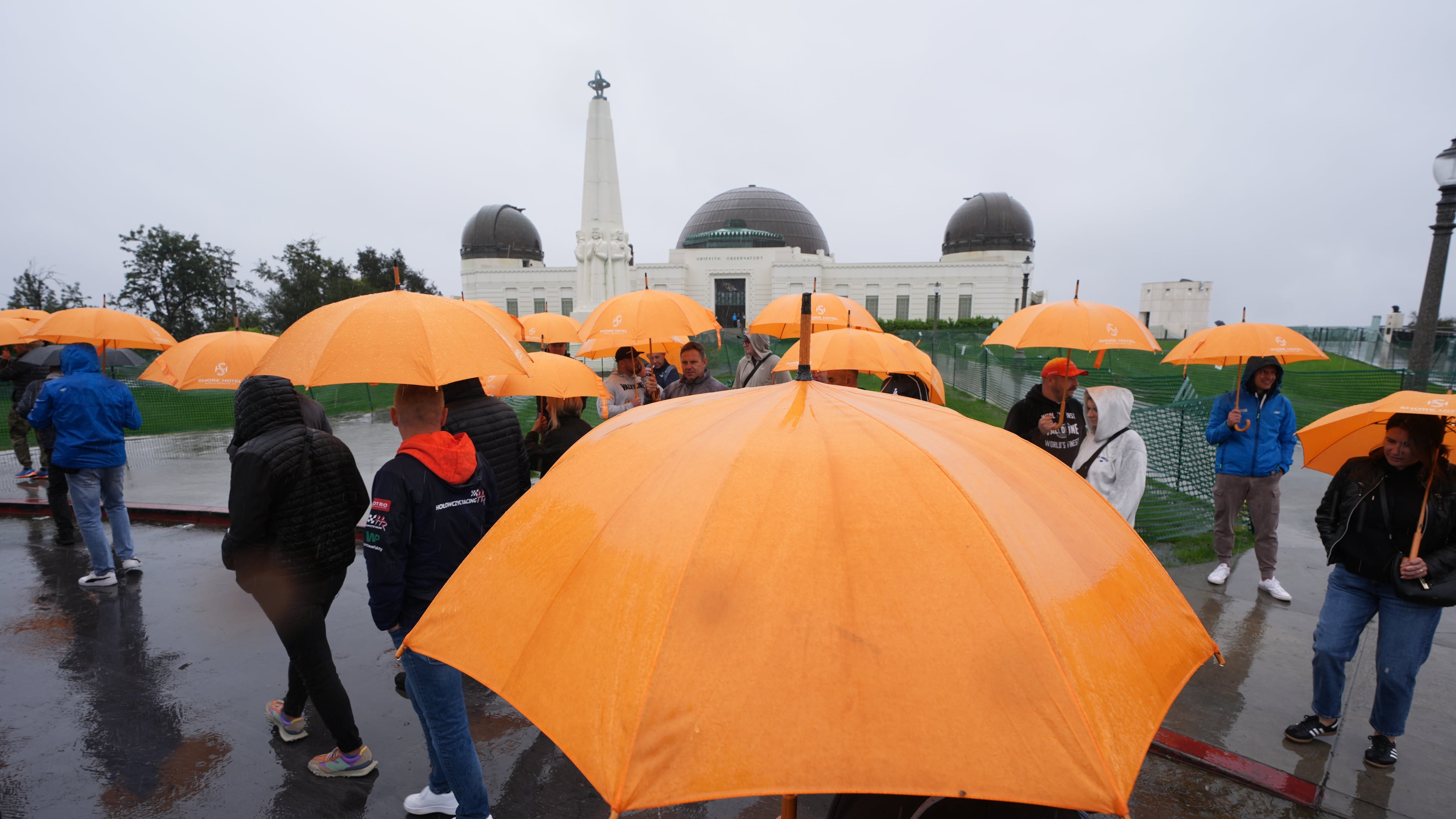 Tourists from Poland carry umbrellas as rain falls while visiting the Griffith Observatory Tuesday, Oct. 14, 2025, in Los Angeles. (AP Photo/Damian Dovarganes)