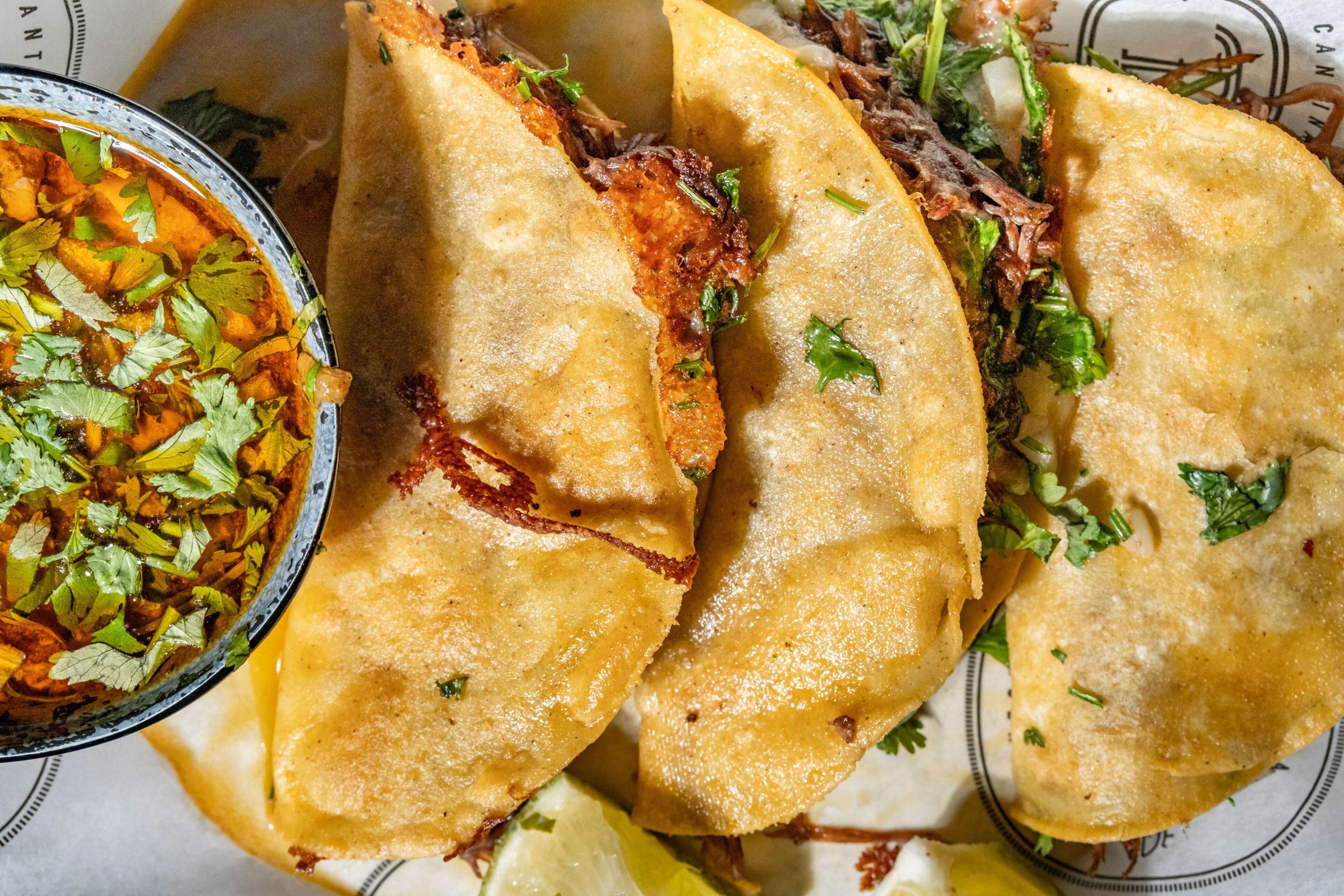 Quesabirria tacos at CT Cantina are served with the traditional side of consommé for dipping. (Courtesy of CT Cantina & Taqueria)