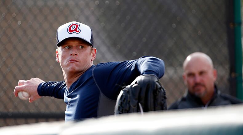 Braves manager Fredi Gonzalez (background) watches as pitcher Gavin Floyd takes part in throwing exercises during a spring training baseball workout Thursday in Lake Buena Vista, Fla.