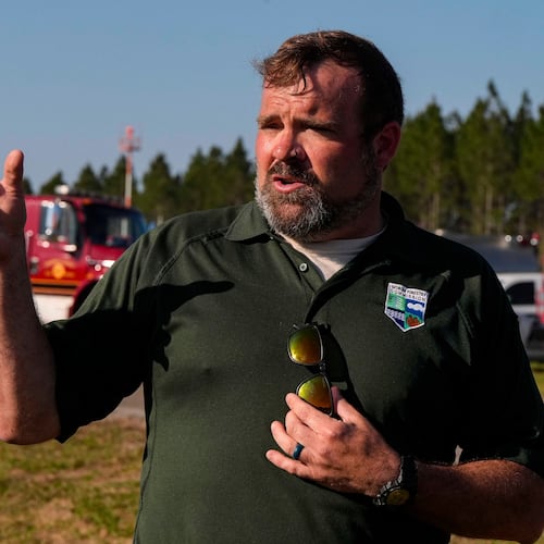 Seth Hawkins with the Georgia Forestry commision speaks to the media as fire crews and truck assemble at the Brantley County Airport as they work the Brantley highway 82 fire, Thursday, April 23, 2026, near Nahunta, Ga. (AP Photo/Mike Stewart)