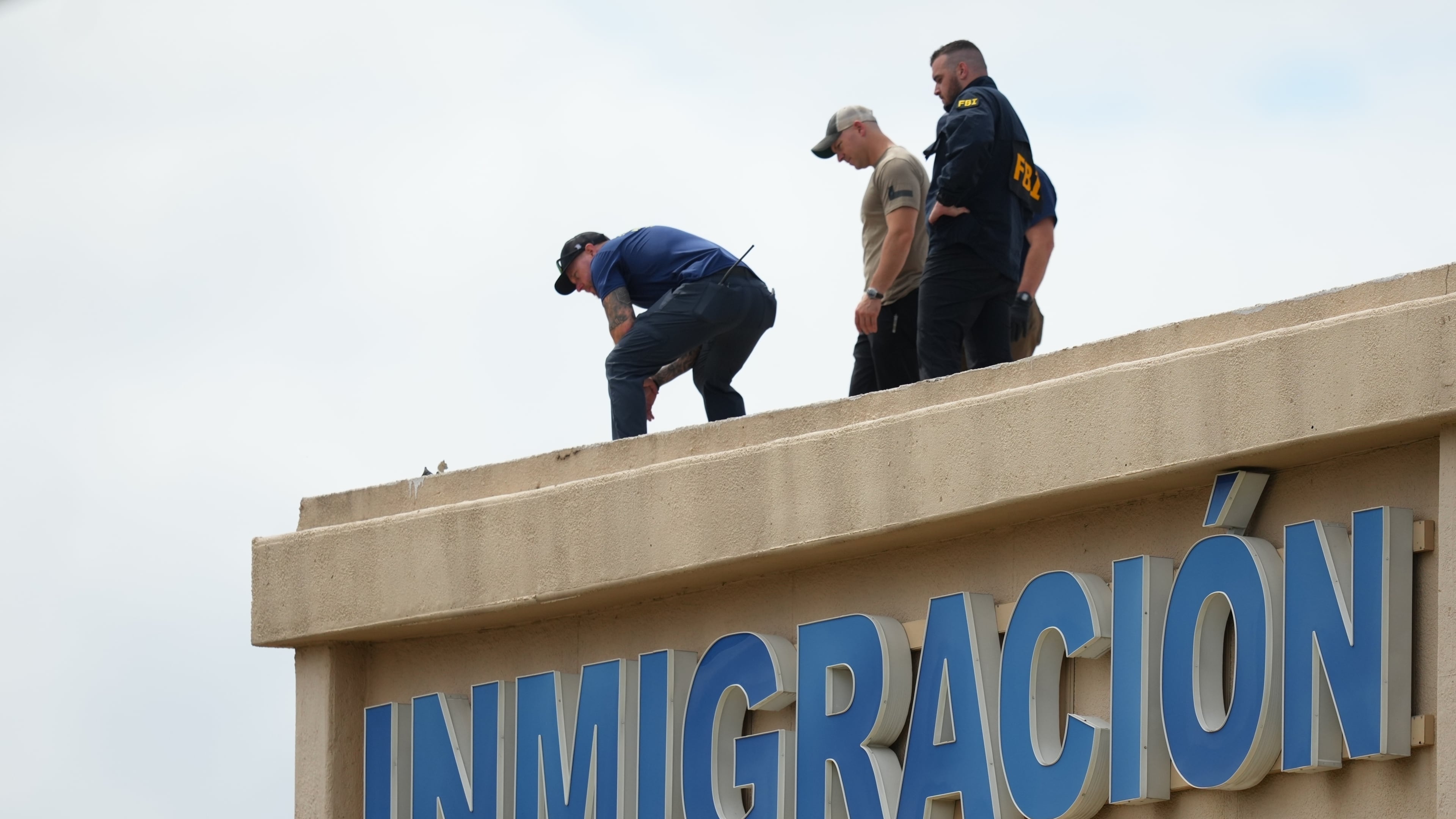 Law enforcement agents look around the roof of a building near the scene of a shooting at a U.S. Immigration and Customs Enforcement office in Dallas on Wednesday, Sept. 24, 2025. (AP Photo/Julio Cortez)