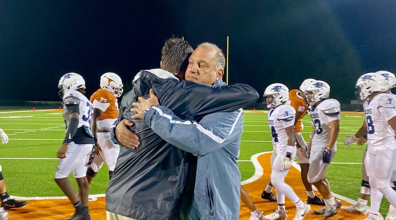Norcross High coach Keith Maloof hugs his son Tyler Maloof, the coach at Lanier High, after the Blue Devils' 31-10 win at Lanier August 16, 2024. It was the first father-son coaching matchup in GHSA football since 2006. (AJC photo by Ken Sugiura)
